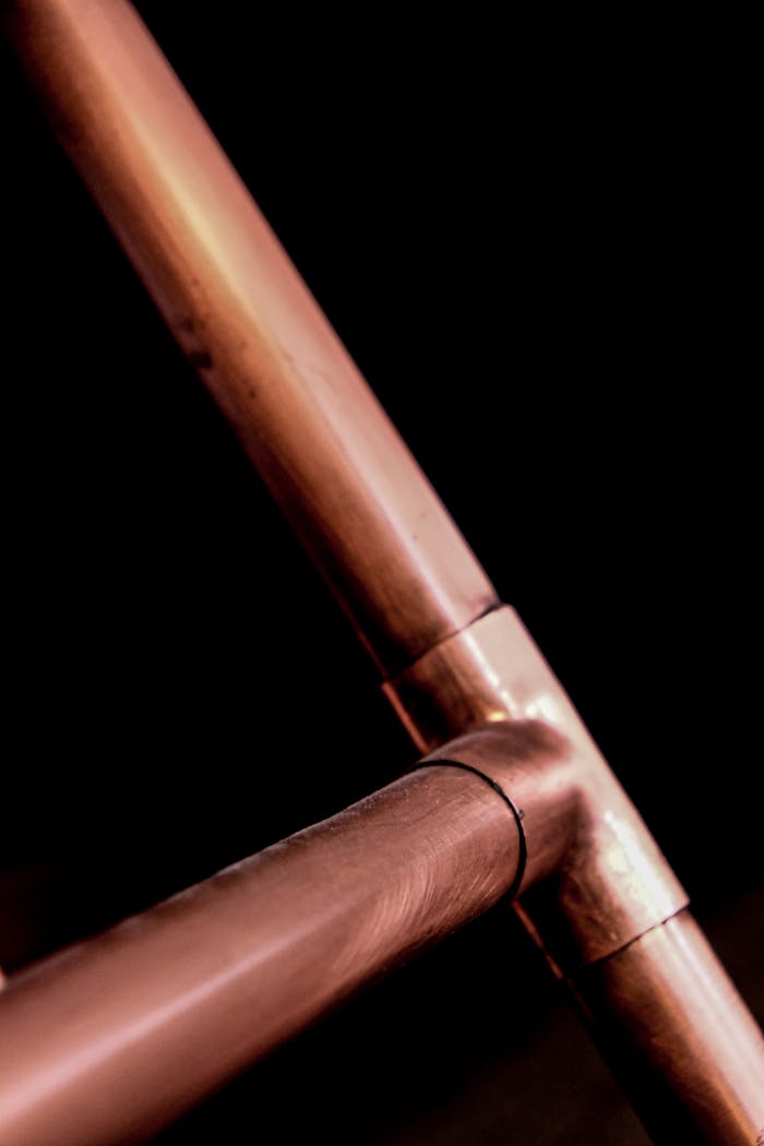 Industrial copper pipes close-up with a dark background, highlighting metallic textures.